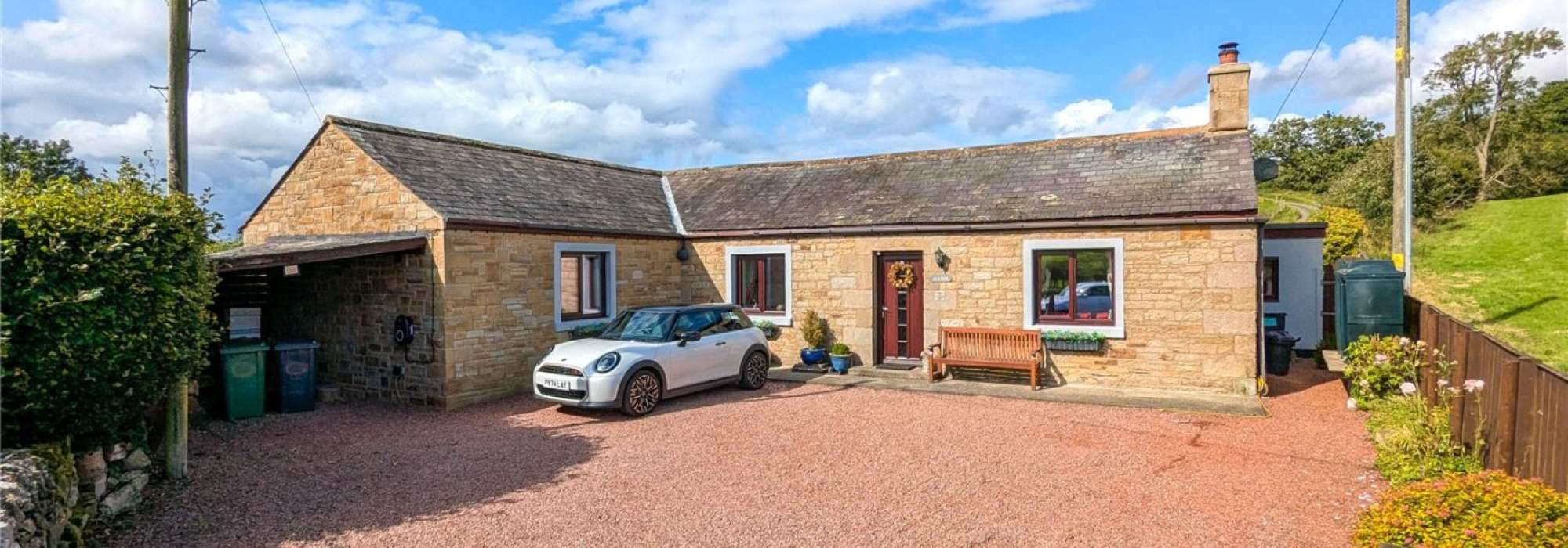 Brown bungalow with a car outside.