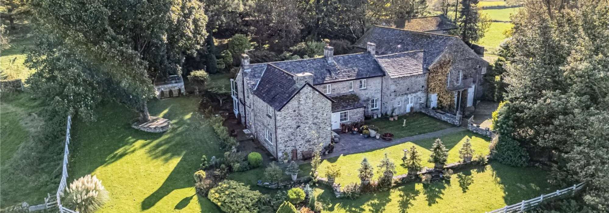 Large grey house surrounded by greenery.