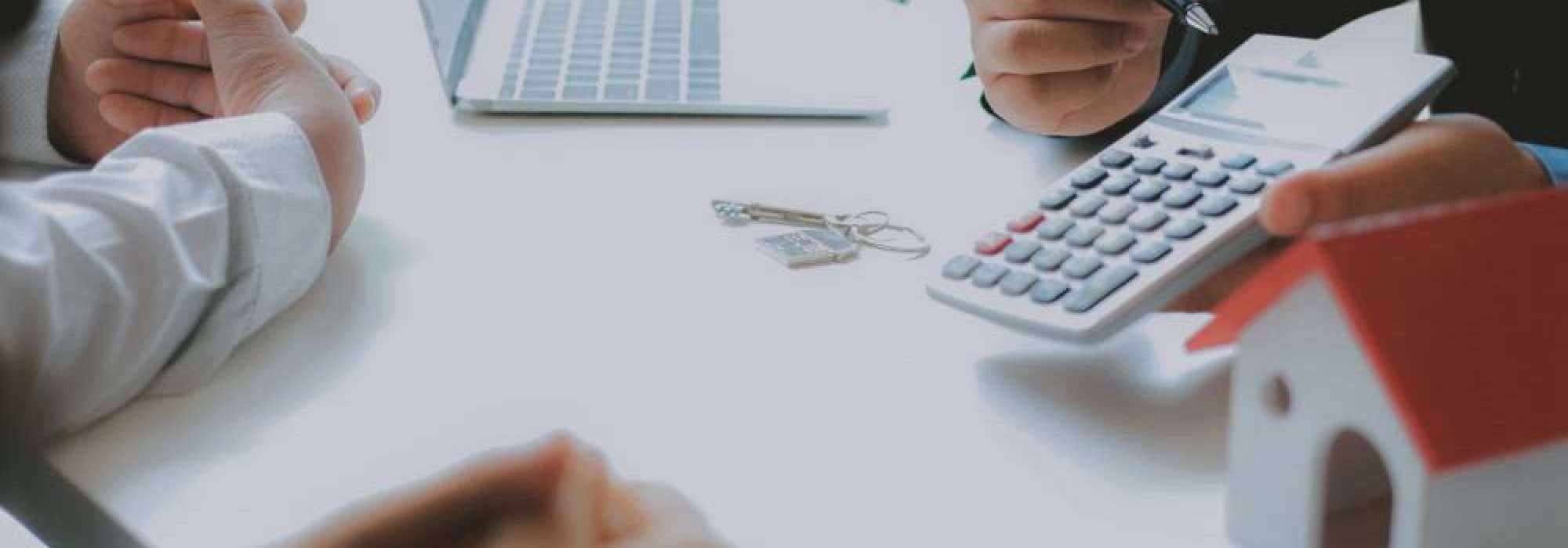 People sitting at a desk with a laptop and a calculator 