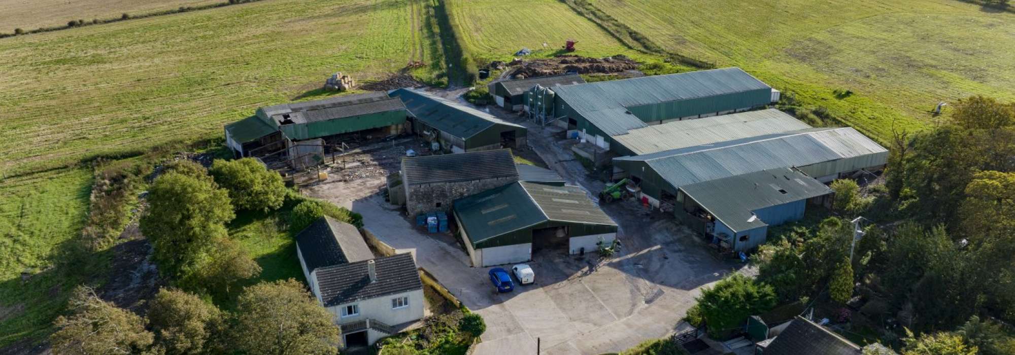 Drone image of Croftlands Farm which includes a house and many outbuildings and lots of land surrounding the property. 
