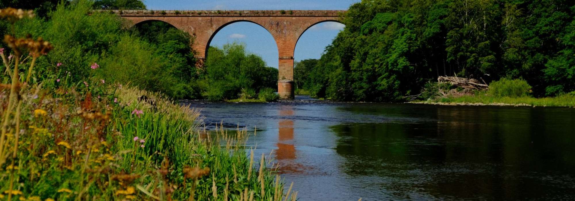River Eden flowing underneath large stone arch bridge at Wetheral, Cumbria. 